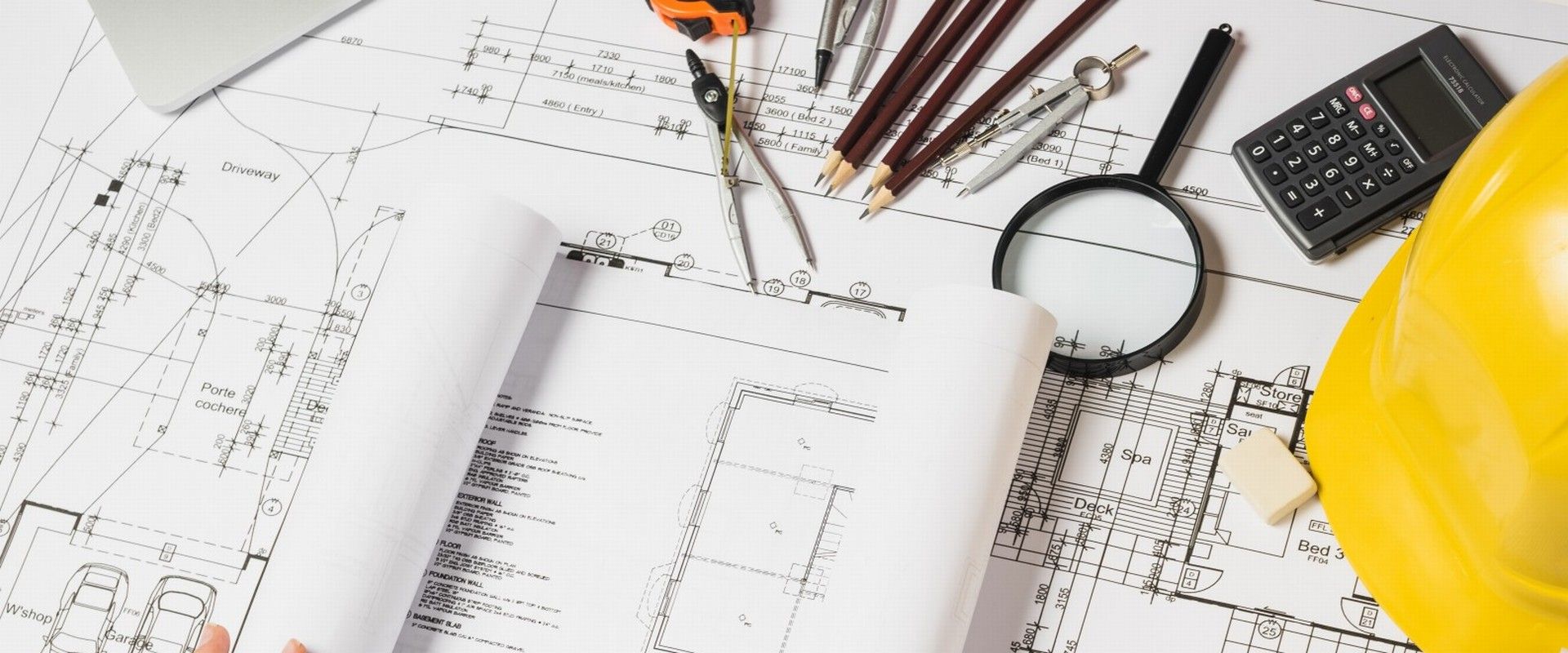 Planos arquitectónicos con casco de seguridad amarillo y herramientas de trabajo de Constructora Inteligente